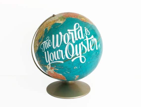 The world's your oyster quote on a globe, with white background